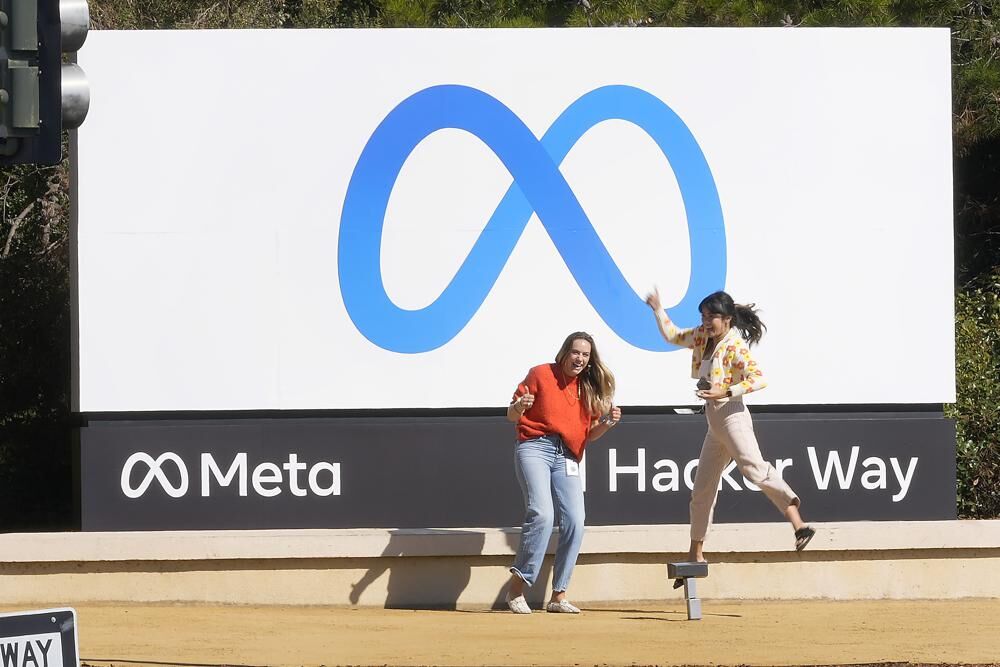 Facebook employees take a photo with the company's new name and logo outside its headquarters in Menlo Park.jpeg